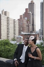 Glamorous African American couple drinking wine on rooftop