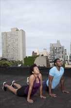 African American couple practicing yoga on rooftop