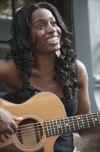 African American woman strumming guitar