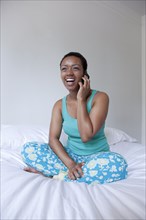 African American talking on cell phone in bed