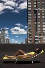 Black woman sunbathing on urban rooftop