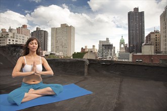 Mixed race woman practicing yoga on rooftop