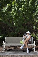 Caucasian woman sitting on park bench with dog
