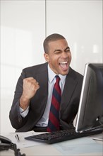 Black businessman cheering at desk