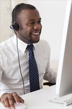 Black businessman in headset working at desk