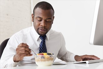 Black businessman eating breakfast at desk