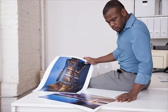Black businessman looking at photographs in office
