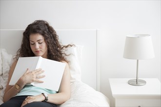 Caucasian woman sleeping in bed holding book