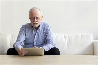 Caucasian man using tablet computer on sofa