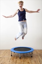 Caucasian woman jumping on indoor trampoline