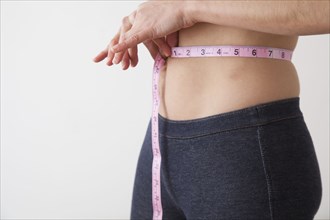 Caucasian woman measuring her waistline