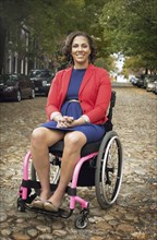 Disabled woman smiling in wheelchair on cobblestone street