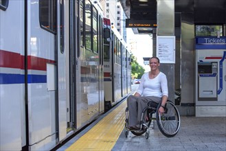 Disabled woman in wheelchair waiting in train station