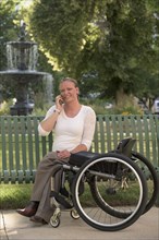 Disabled woman with wheelchair sitting on bench