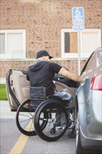 Disabled man in wheelchair climbing into car
