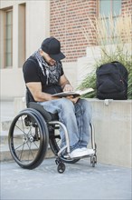 Disabled student in wheelchair reading book