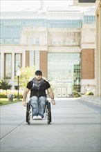 Disabled student rolling in wheelchair on college campus