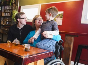 Paraplegic mother holding son in tea shop