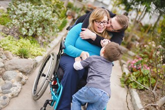 Paraplegic woman and family hugging in garden