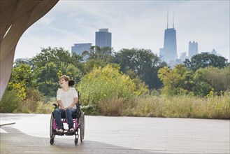 Paraplegic woman sitting in wheelchair under city skyline