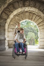 Mother pushing paraplegic daughter in wheelchair