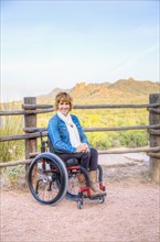Paraplegic woman in wheelchair in scenic landscape