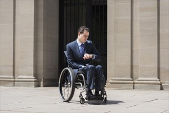 Paraplegic businessman in wheelchair checking watch