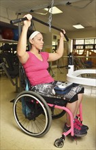 Paraplegic woman in wheelchair working out in physical therapy