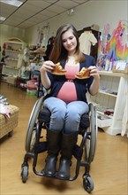 Pregnant paraplegic woman in wheelchair shopping in baby store