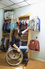 Pregnant paraplegic woman in wheelchair shopping in baby store