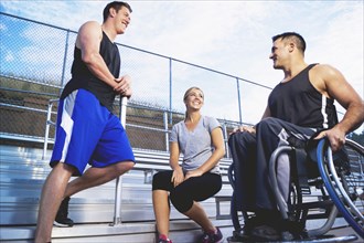 Paraplegic athlete in wheelchair with friends on bleachers