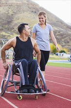 Paraplegic athlete in wheelchair with girlfriend on track