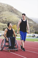 Paraplegic athlete in wheelchair with friend on track