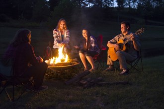 Family playing music at campfire