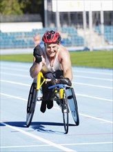 Smiling man racing in wheelchair on track