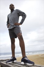 Black man standing on bench at beach