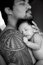 Tattooed father holding newborn baby