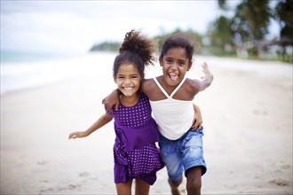 Mixed race sisters hugging on beach