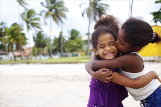 Mixed race sisters hugging on beach