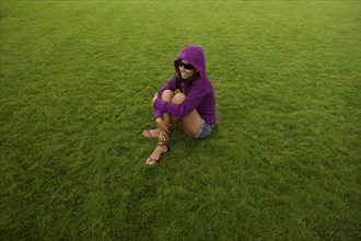Smiling Hispanic woman sitting in grass