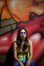 Hispanic woman standing near graffiti wall making face