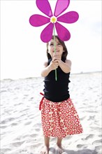 Hispanic girl playing with toy flower on beach