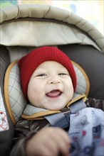 Grinning mixed race baby in car seat