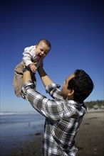 Father lifting baby on beach