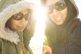 Mixed race sisters in sunglasses and hoods