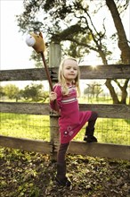 Caucasian girl holding stick horse near fence