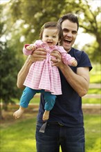 Father holding toddler daughter in park