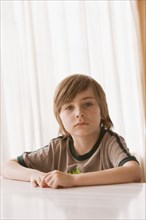 Hispanic boy sitting at table and looking serious