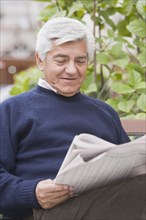 Senior Hispanic man reading newspaper