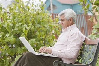 Senior Hispanic man typing on laptop